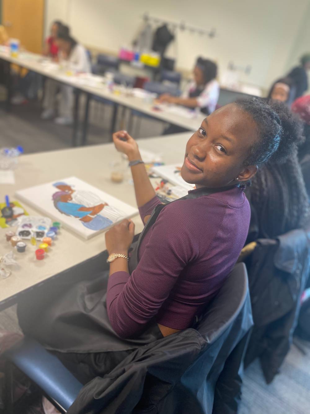 Student painting various colors and posing for picture